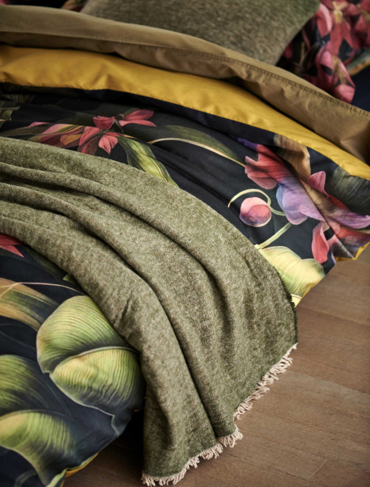 detail shot van een dekbedovertrek met bloemen en een plaid in een groene kleur