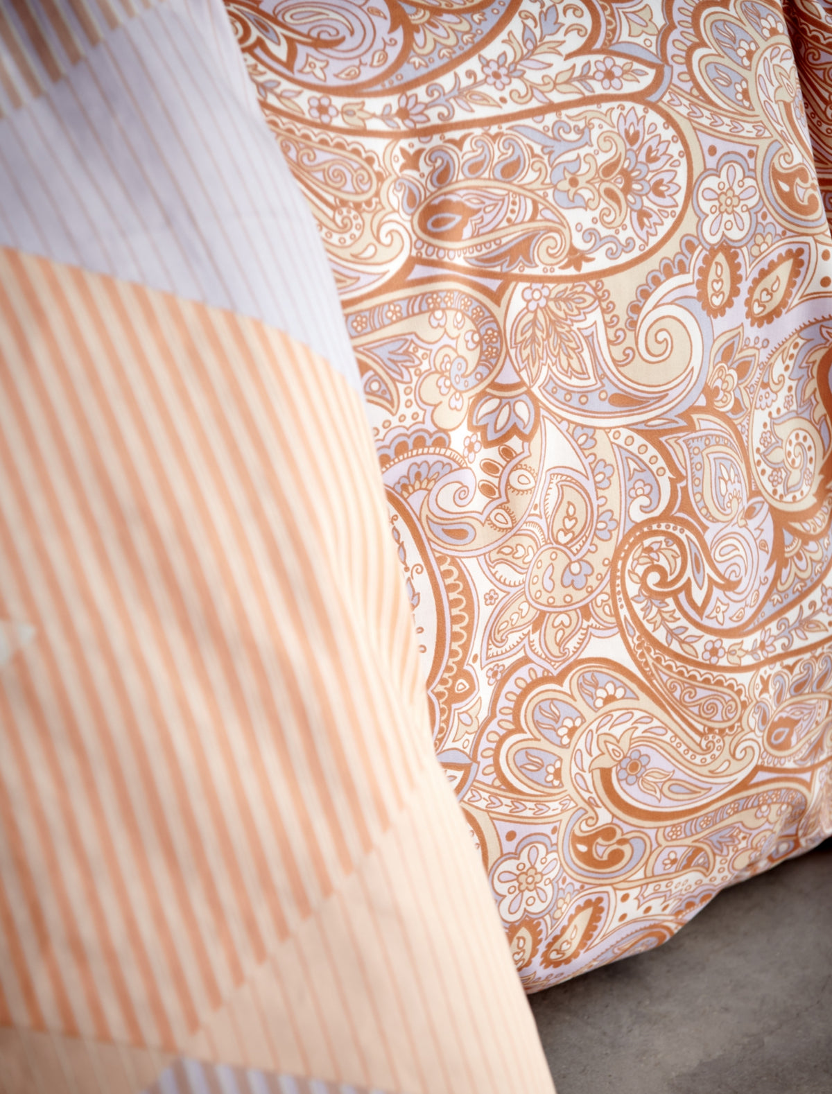 detail shot van een dekbedovertrek in een paisley print in paarse en oranje kleuren