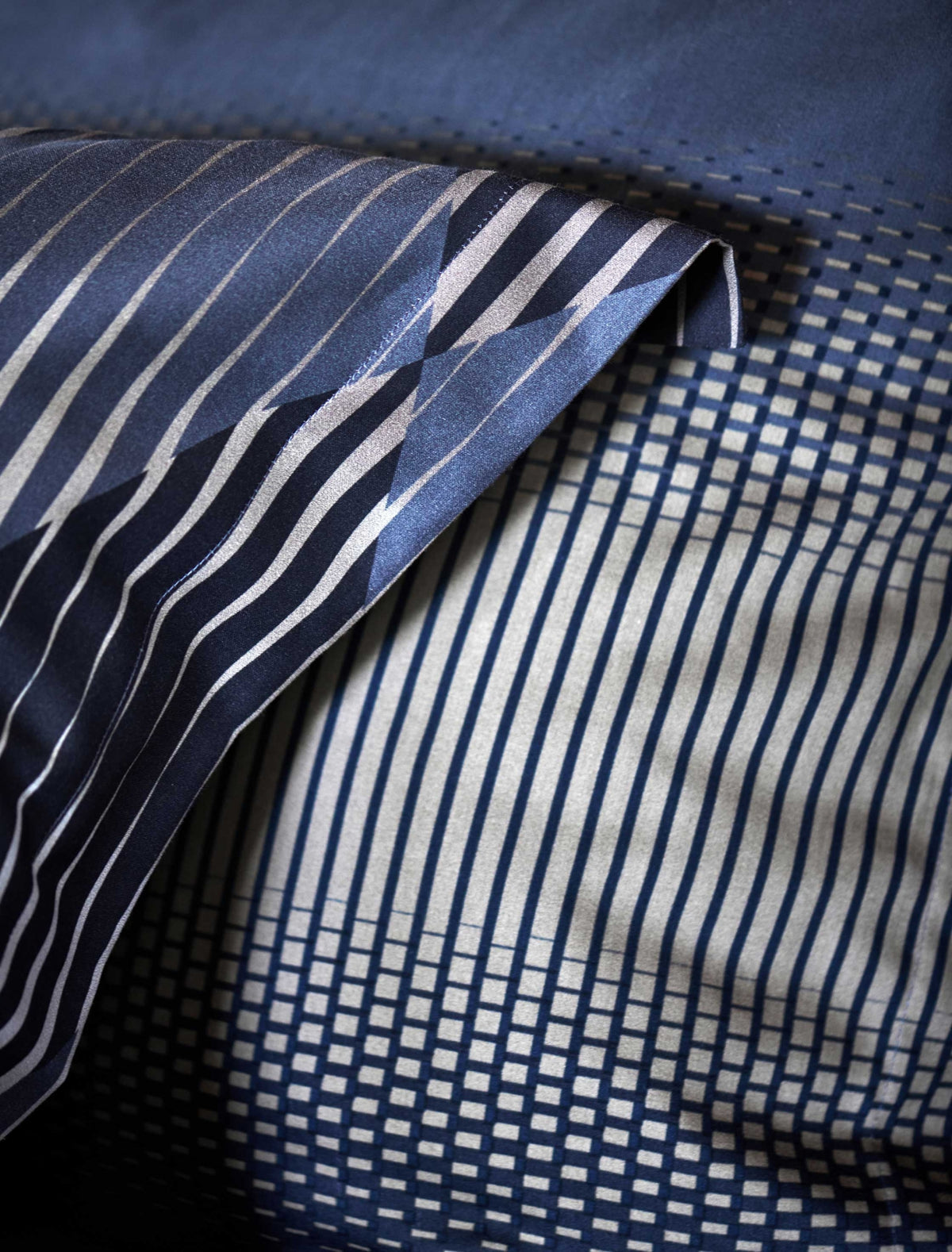 detail shot van een hoofdkussen met grafische print in grijze en donkerblauwe kleuren