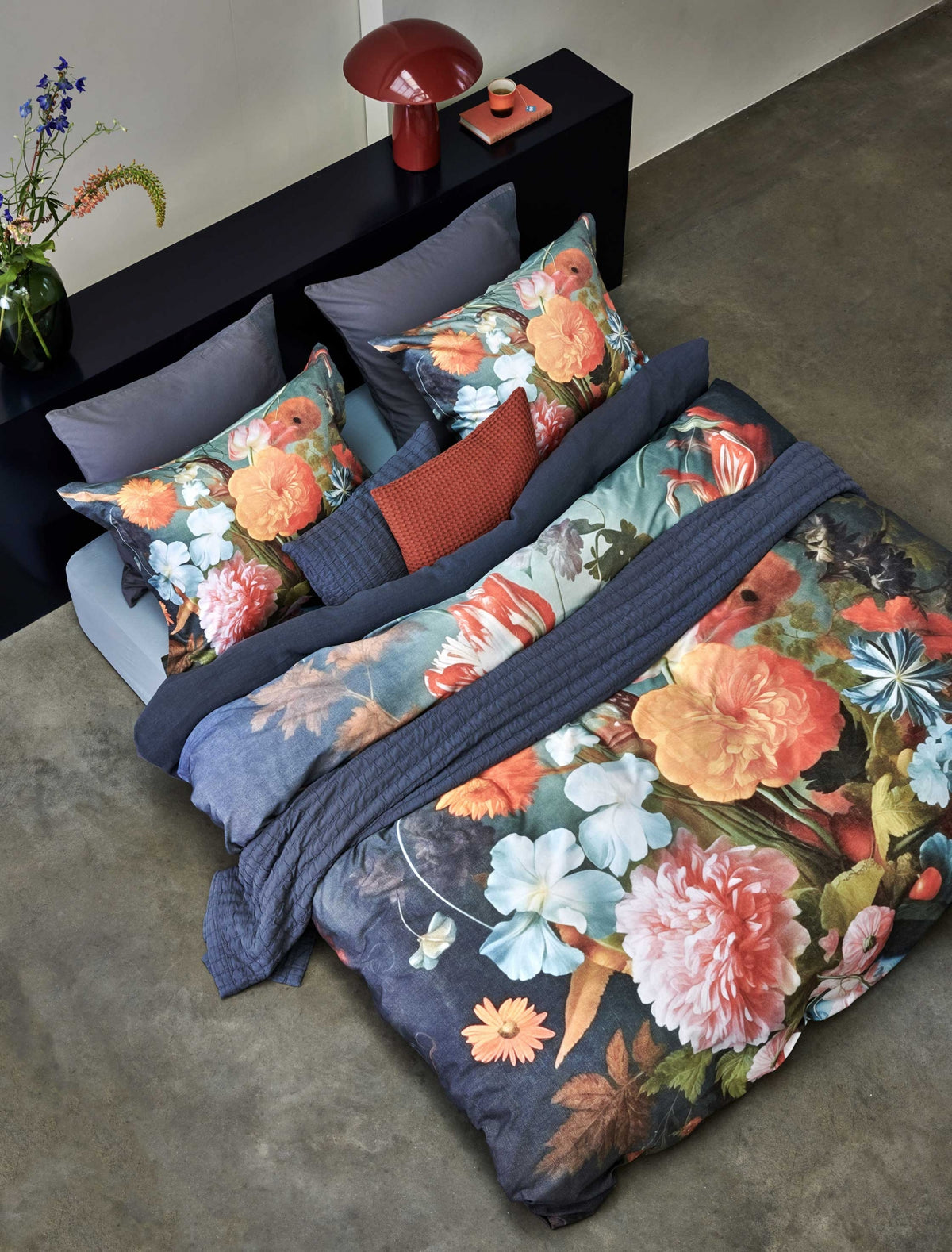 Dreamscape multi dekbedovertrek heeft een boeket met roze en oranje bloemen tegen een blauwe achtergrond. De achterkant van het dekbedovertrek is effen donkerblauw. De kussens hebben aan beide zijden dezelfde bloemen, maar dan iets kleiner.